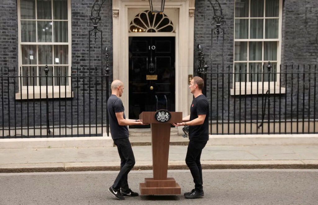 Two men carry a lectern out into Downing Street for a speech by the Prime Minister